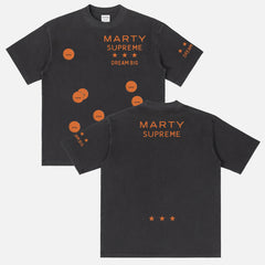 Retro Marty Supreme movie washed black graphic tee shirt with front back and sleeve print of orange movie poster logo, ping pong balls, and dream big 