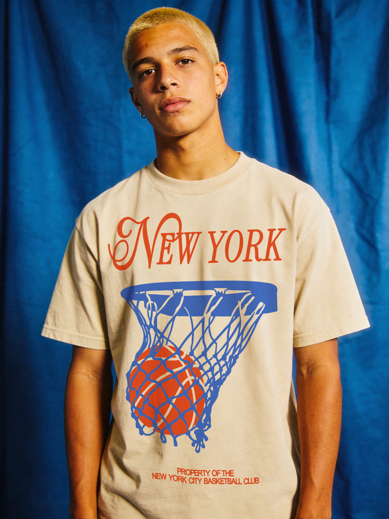 Off white New York Knicks t-shirt with retro orange and royal blue streetwear art and retro jersey lettering on a unisex comfort colors graphic tee