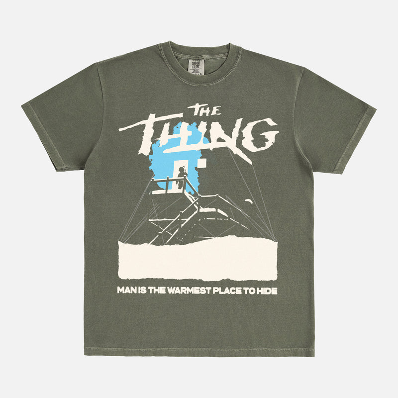 John Carpenter's The Thing 1982 graphic t-shirt with cabin snow art on a heavyweight green graphic tee